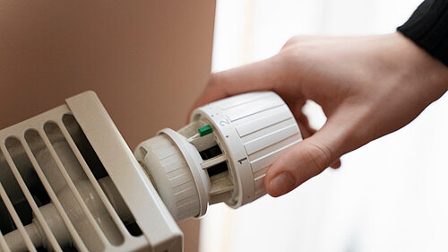 Person adjusting a radiator thermostat